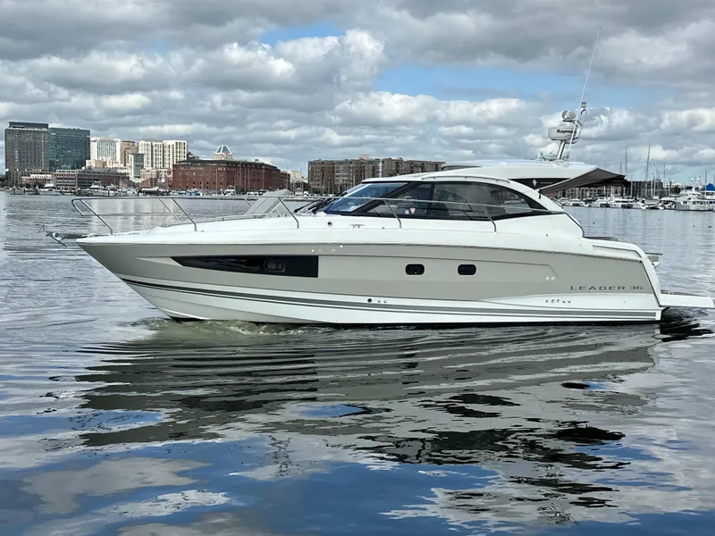 Slide: The Image of 2016 Jeanneau Leader 36 yacht cruising in a harbor with city skyline backdrop. - 0
