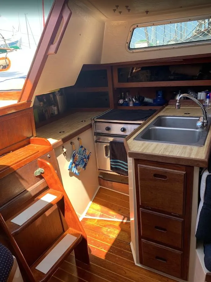 Slide: The Image of 1984 Catalina 38 yacht interior kitchen with wooden cabinetry, stove, and sink. - 23
