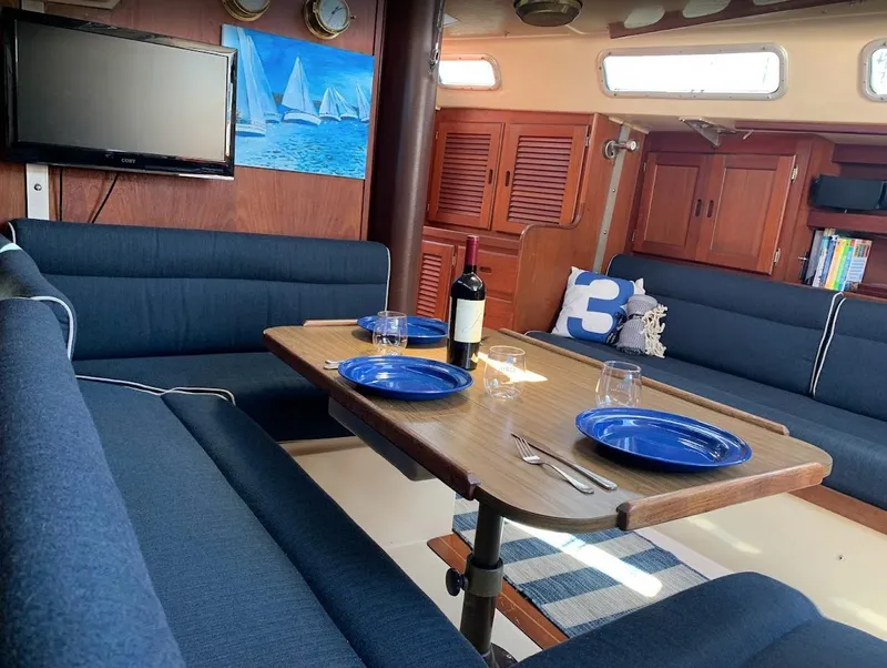 Slide: The Image of Interior of 1984 Catalina 38 sailboat with dining table, blue seating, and nautical decor. - 24