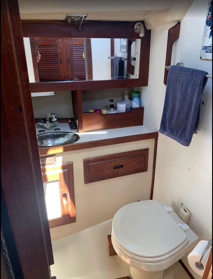 Slide: The Image of 1984 Catalina 38 boat bathroom with wooden cabinets, mirror, sink, and toilet. - 26