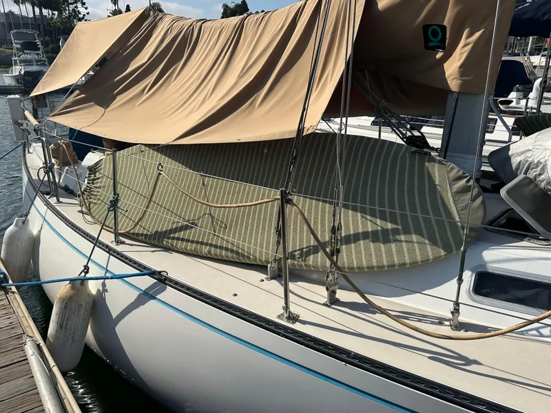 Slide: The Image of 1984 Catalina 38 sailboat docked, covered with beige and striped tarps. - 3
