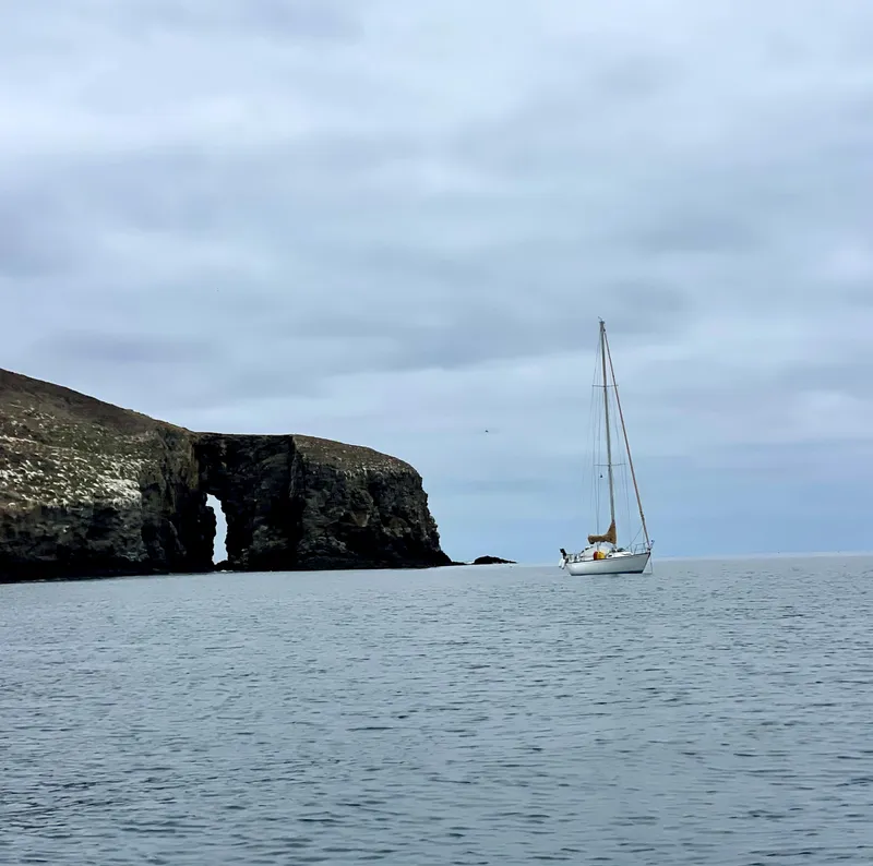Slide: The Image of Sailboat Catalina 38 (1984) near rocky arch, overcast sky, calm sea. - 5