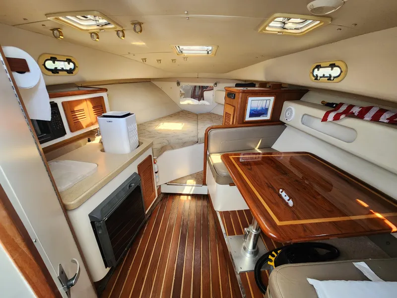 Slide: The Image of Interior of 2003 Pursuit 3000 Express boat with wood accents and cozy seating area. - 10