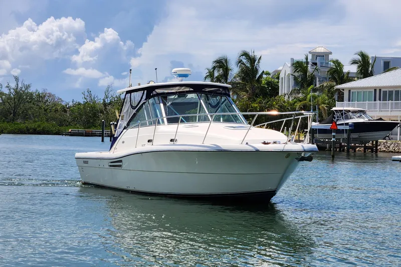 Slide: The Image of 2003 Pursuit 3000 Express boat cruising on a sunny day near waterfront homes. - 14