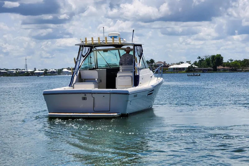 Slide: The Image of 2003 Pursuit 3000 Express boat cruising on a sunny day with scenic waterfront views. - 15