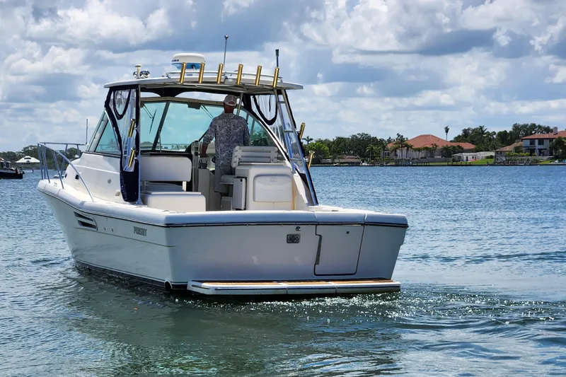 Slide: The Image of 2003 Pursuit 3000 Express boat cruising on a sunny day with scenic waterfront homes. - 19