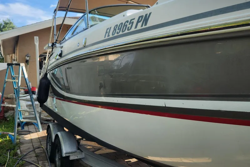 Slide: The Image of 2013 Hurricane SD2400 OB boat on trailer, parked near a house with a ladder. - 18
