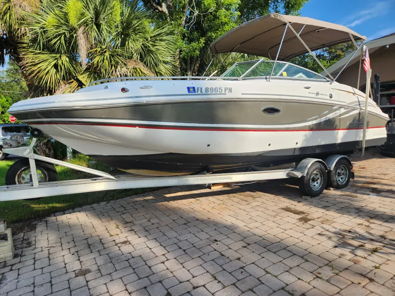 Slide: The Image of 2013 Hurricane SD2400 OB boat on trailer, parked on a paved driveway with lush greenery. - 6