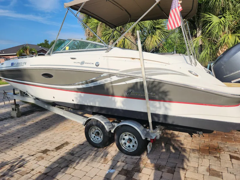 Slide: The Image of 2013 Hurricane SD2400 OB boat on trailer with American flag, parked on paved driveway. - 9