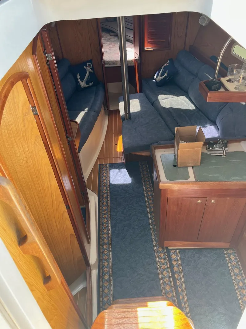 Slide: The Image of Interior of a 2001 Hunter 320 sailboat with blue seating and wooden cabinetry. - 14