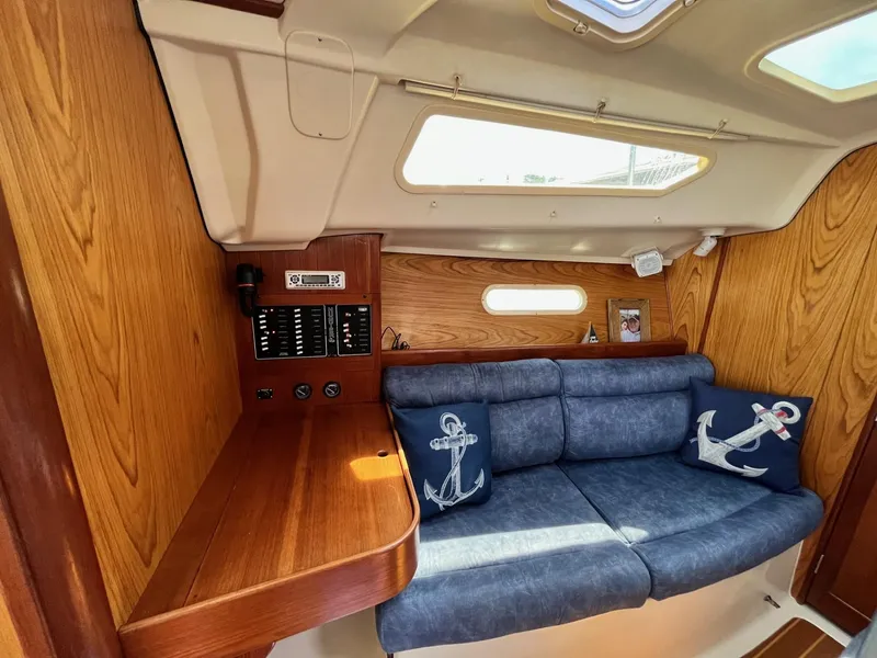 Slide: The Image of Interior of 2001 Hunter 320 sailboat with blue cushioned seating and nautical-themed pillows. - 18