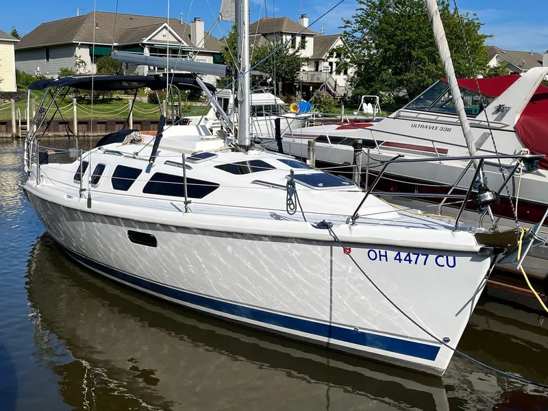 Slide: The Image of 2001 Hunter 320 sailboat docked in a marina, reflecting sunlight on the water. - 5