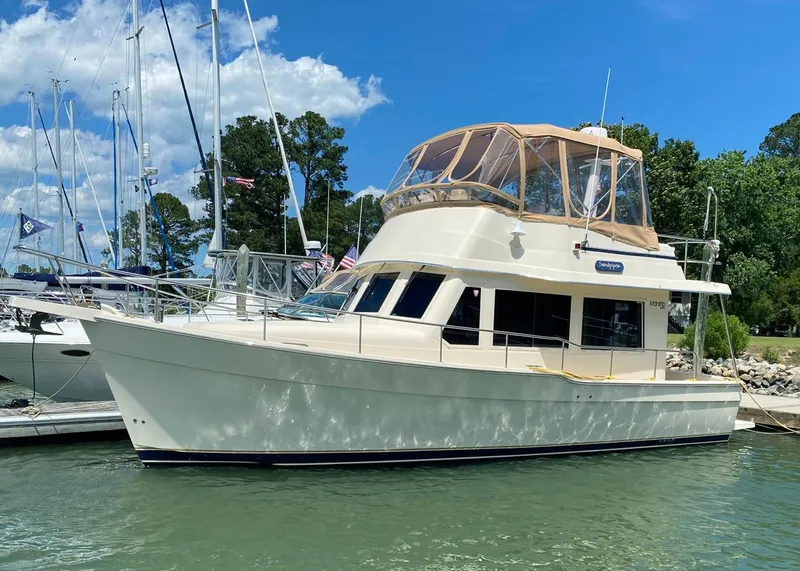 The Image of 2004 Mainship 340 yacht docked at marina under clear blue sky. - 0