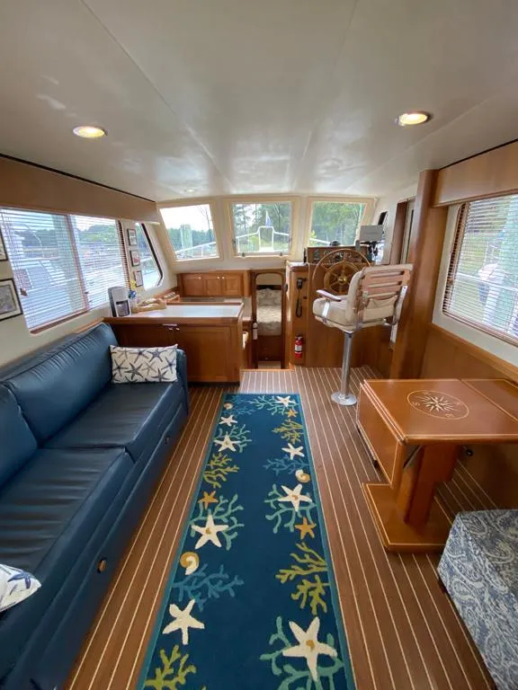Slide: The Image of Interior of 2004 Mainship 340 yacht with blue sofa, nautical rug, and wooden helm. - 2