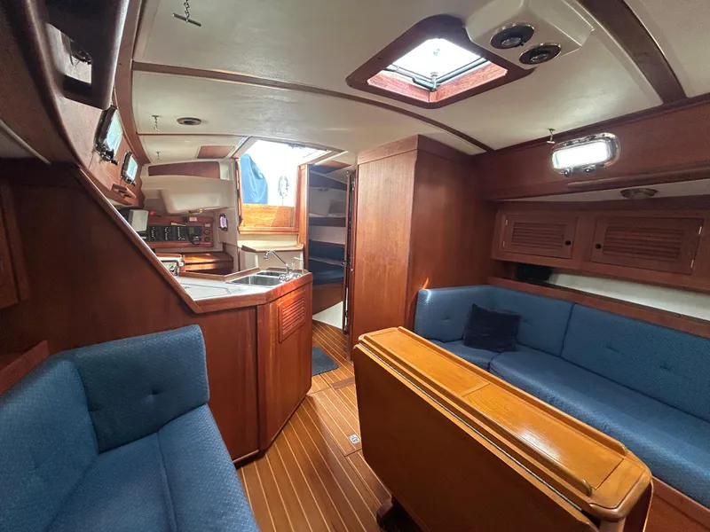 Slide: The Image of Interior of a 1998 Tartan 3500 sailboat with wooden cabinetry and blue seating. - 10