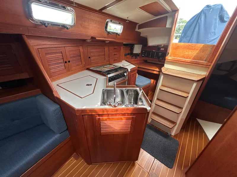 Slide: The Image of Interior of a 1998 Tartan 3500 sailboat featuring a compact kitchen and wooden cabinetry. - 13