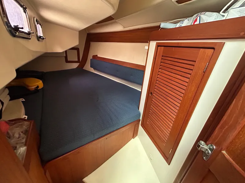 Slide: The Image of 1998 Tartan 3500 yacht cabin with blue bedding and wooden storage. - 15