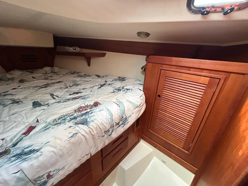 Slide: The Image of Cozy cabin interior of 1998 Tartan 3500 sailboat with wooden cabinetry and nautical bedding. - 20