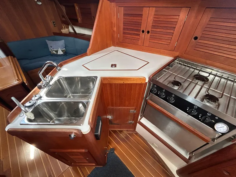 Slide: The Image of 1998 Tartan 3500 yacht kitchen with dual sinks, stove, and wooden cabinetry. - 9
