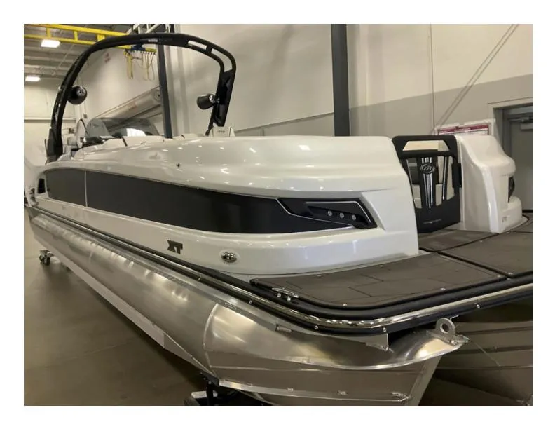 The Image of 2025 Manitou XT pontoon boat in showroom, sleek design, white and black exterior. - 0