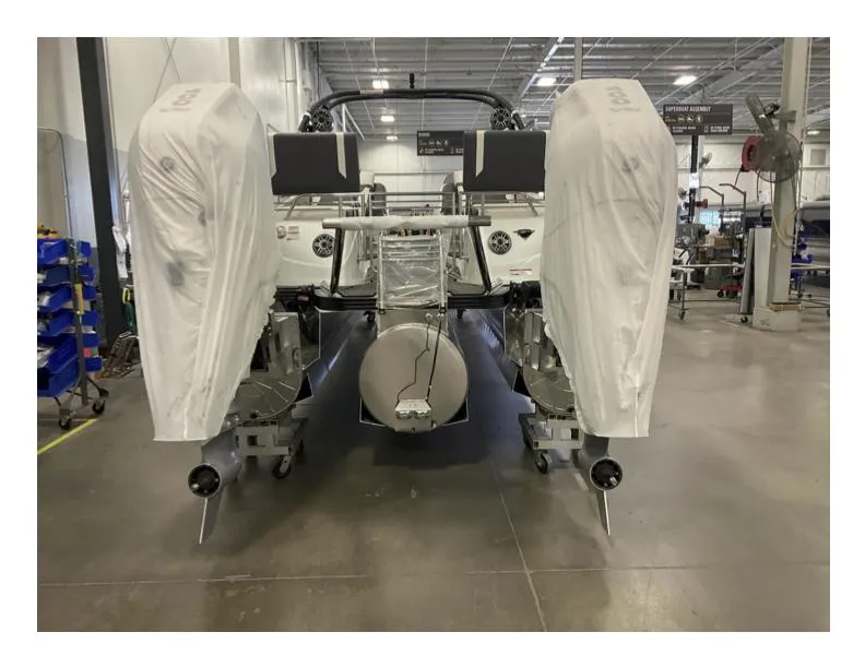 Slide: The Image of 2025 Manitou XT boat in a factory, covered engines, industrial setting. - 2