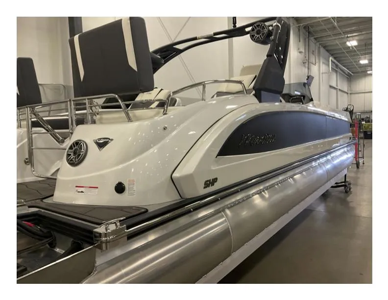 Slide: The Image of 2025 Manitou XT pontoon boat in showroom, featuring sleek design and modern amenities. - 4