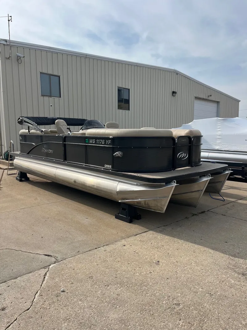 Slide: The Image of 2018 Manitou 23 Oasis RF VP pontoon boat parked outside a warehouse. - 16