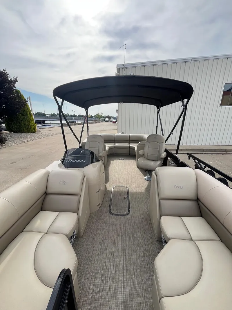 Slide: The Image of 2018 Manitou 23 Oasis RF VP pontoon boat with beige seating and black canopy. - 18