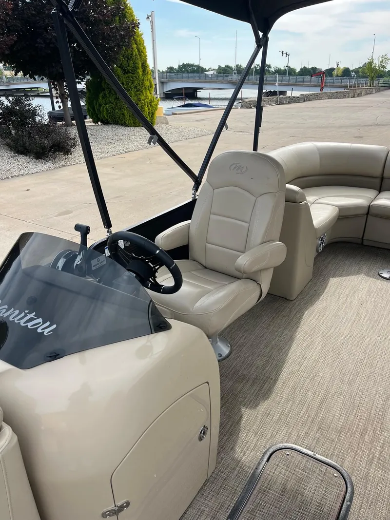 Slide: The Image of 2018 Manitou 23 Oasis RF VP pontoon boat interior with beige seating and steering console. - 20