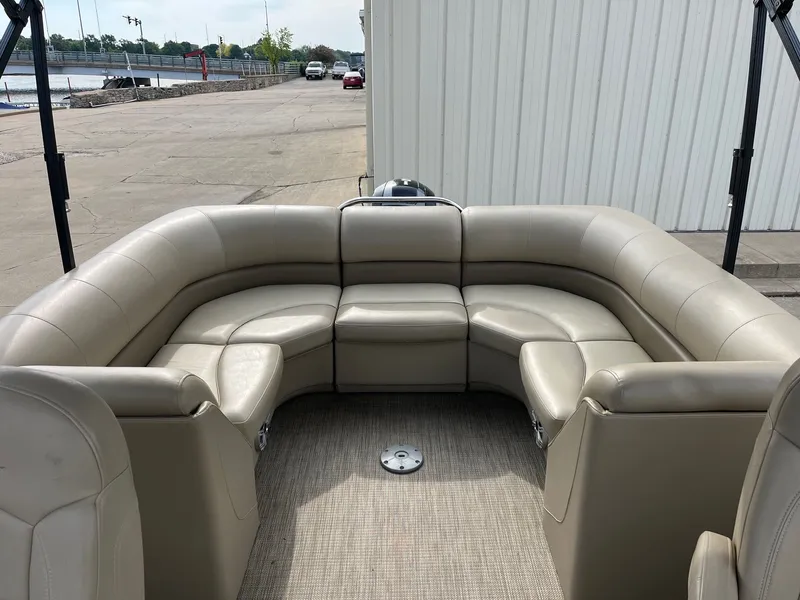 Slide: The Image of 2018 Manitou 23 Oasis RF VP pontoon boat with beige seating, docked near a waterfront. - 21
