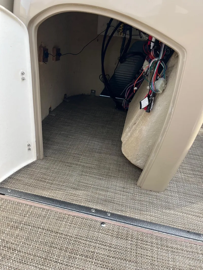 Slide: The Image of 2018 Manitou 23 Oasis RF VP storage compartment with wiring and carpeted interior. - 4