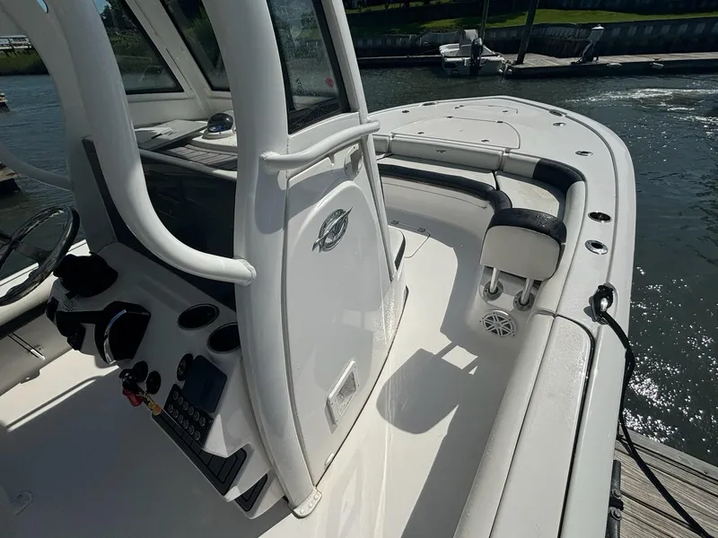 Slide: The Image of 2023 Tidewater 2500CB boat interior, featuring helm and seating, docked by the water. - 17