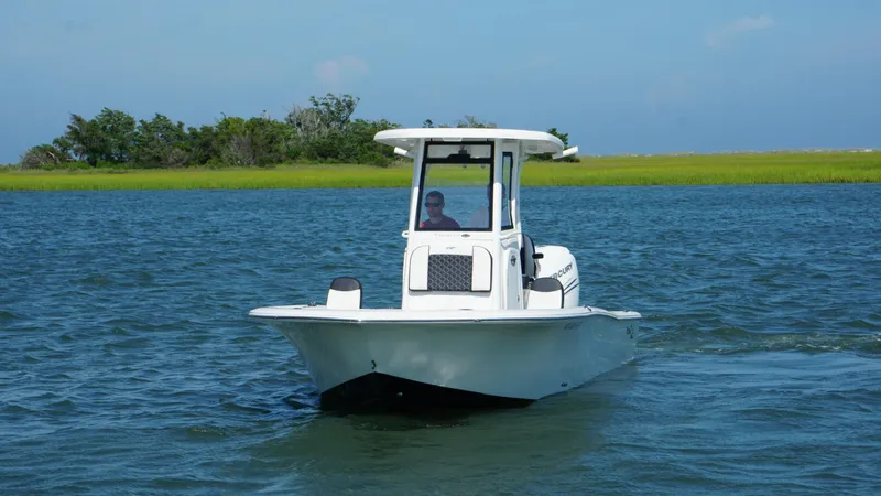 Slide: The Image of 2023 Tidewater 2500CB boat cruising on a serene lake with lush greenery. - 20
