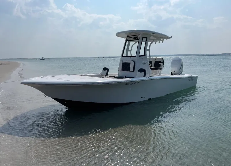 Slide: The Image of 2023 Tidewater 2500CB boat anchored on a sandy beach with clear blue water. - 4