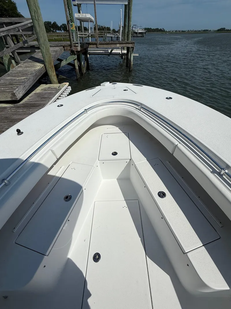 Slide: The Image of 2017 Onslow Bay 27 boat bow with seating, docked by a wooden pier. - 4