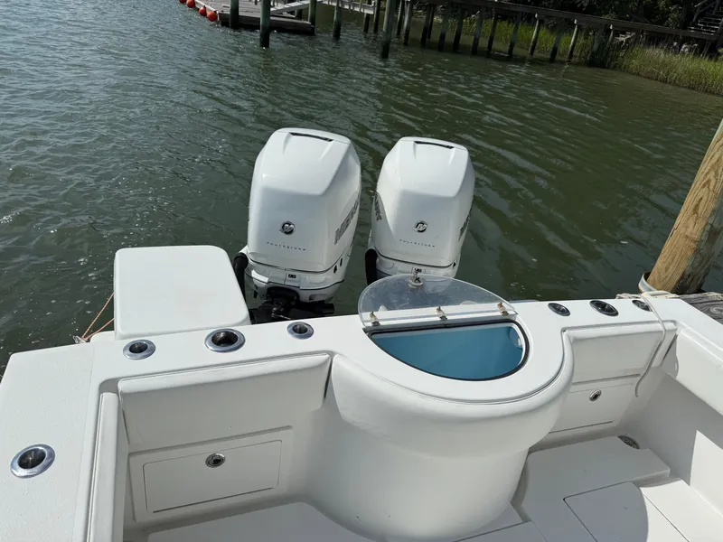 Slide: The Image of 2017 Onslow Bay 27 boat with dual outboard motors docked by the water. - 7