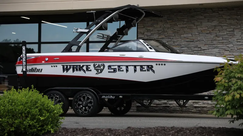 Slide: The Image of 2013 Malibu Wakesetter 20 VTX boat on trailer, parked near stone wall. - 0