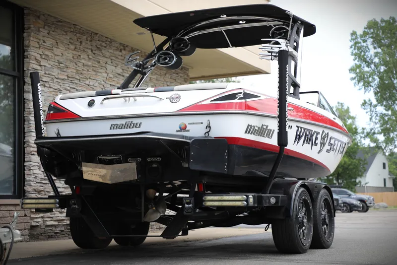Slide: The Image of 2013 Malibu Wakesetter 20 VTX boat on trailer, rear view, parked near stone building. - 7