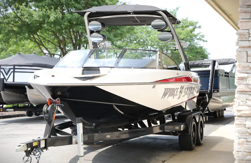 Slide: The Image of 2013 Malibu Wakesetter 20 VTX boat on trailer, parked outdoors near trees. - 9