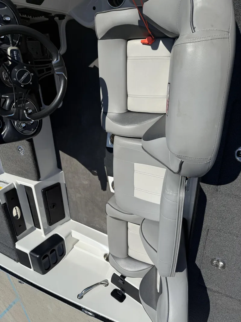 Slide: The Image of 2023 Triton 19 TrX Patriot boat interior with gray seating and steering wheel. - 12