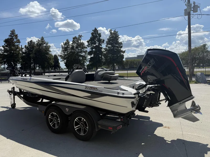 Slide: The Image of 2023 Triton 19 TrX Patriot boat on trailer, outdoors under a sunny sky. - 16