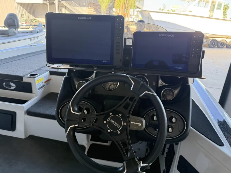 Slide: The Image of 2023 Triton 19 TrX Patriot boat dashboard with Lowrance HDS displays and steering wheel. - 19
