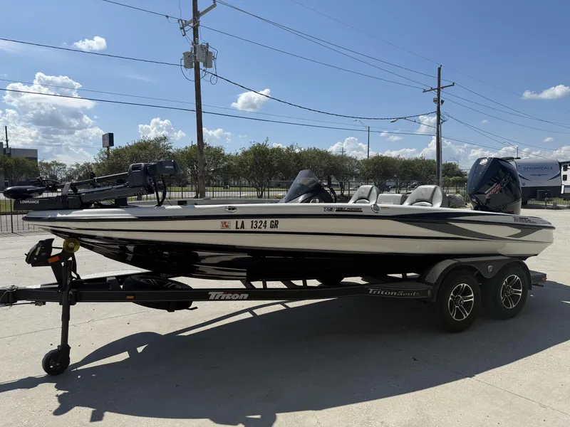 Slide: The Image of 2023 Triton 19 TrX Patriot boat on trailer under clear blue sky. - 20