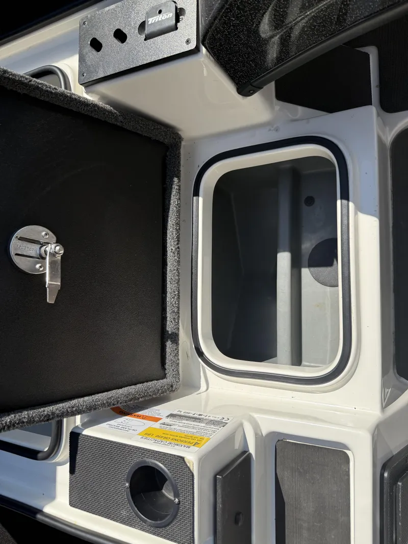 Slide: The Image of 2023 Triton 19 TrX Patriot boat storage compartment with open lid and latch. - 6