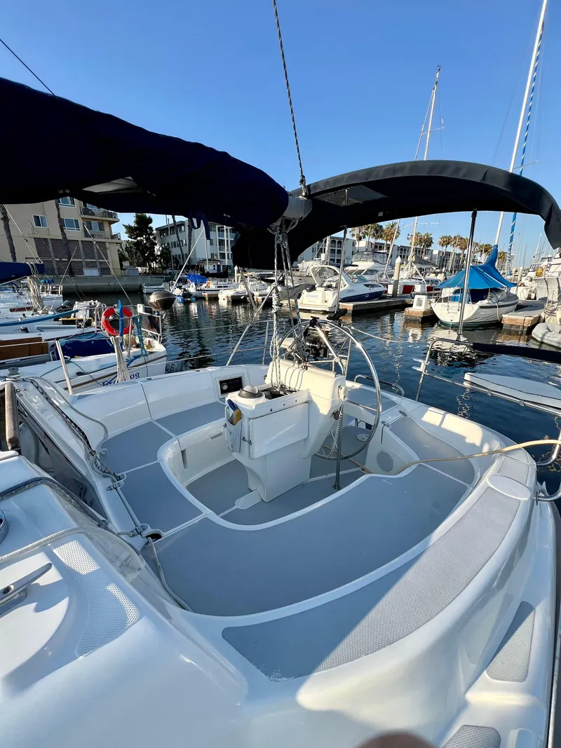 Slide: The Image of 1995 Hunter 29.5 sailboat docked in marina, featuring spacious cockpit and dual bimini covers. - 13