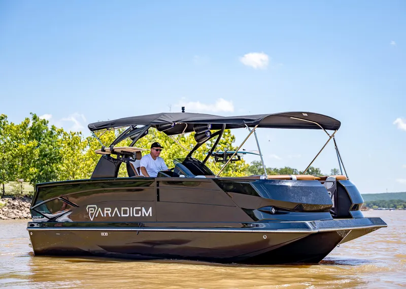 The Image of 2025 Paradigm 236 boat cruising on a sunny day, featuring sleek black design and canopy. - 0