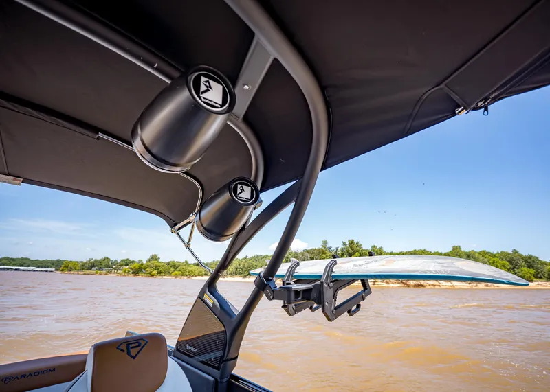 Slide: The Image of 2025 Paradigm 236 boat with speakers and surfboard rack on a sunny day. - 21