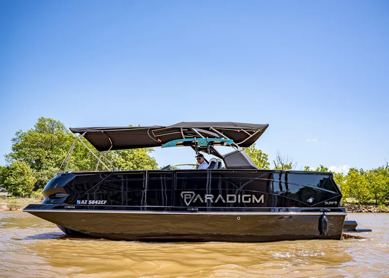 Slide: The Image of 2025 Paradigm 236 boat cruising on a sunny day with lush greenery in the background. - 5