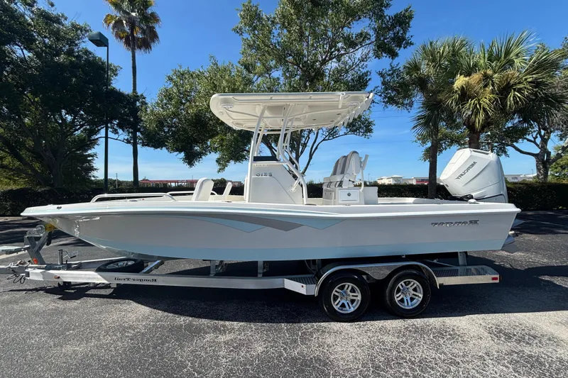 The Image of 2025 Ranger 2510 Bay boat on trailer, parked outdoors under clear blue sky. - 0