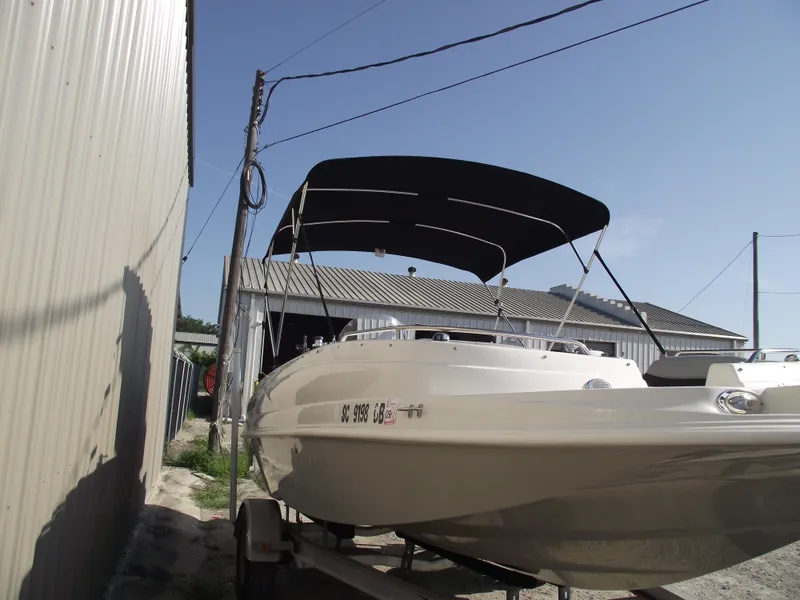Slide: The Image of 2015 Starcraft Limited 2000 OB Fish boat with canopy, parked near a building. - 2